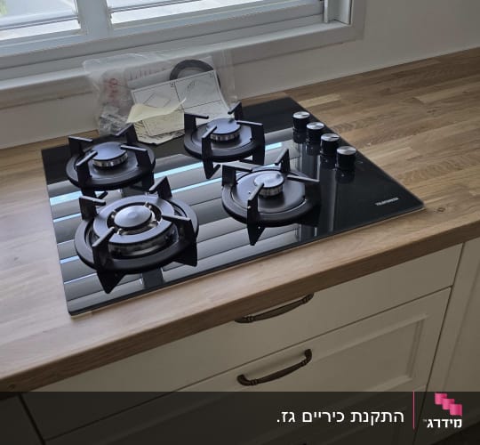 כיריים גז שחורות עם ארבעה מבערים וכפתורים